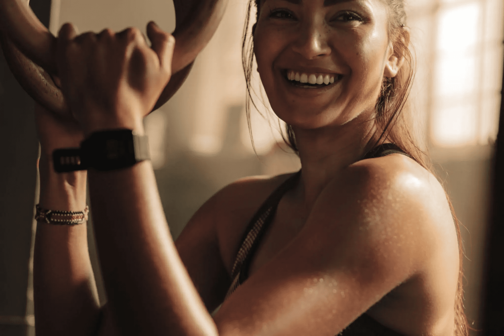 A woman smiling while holding her arm up.