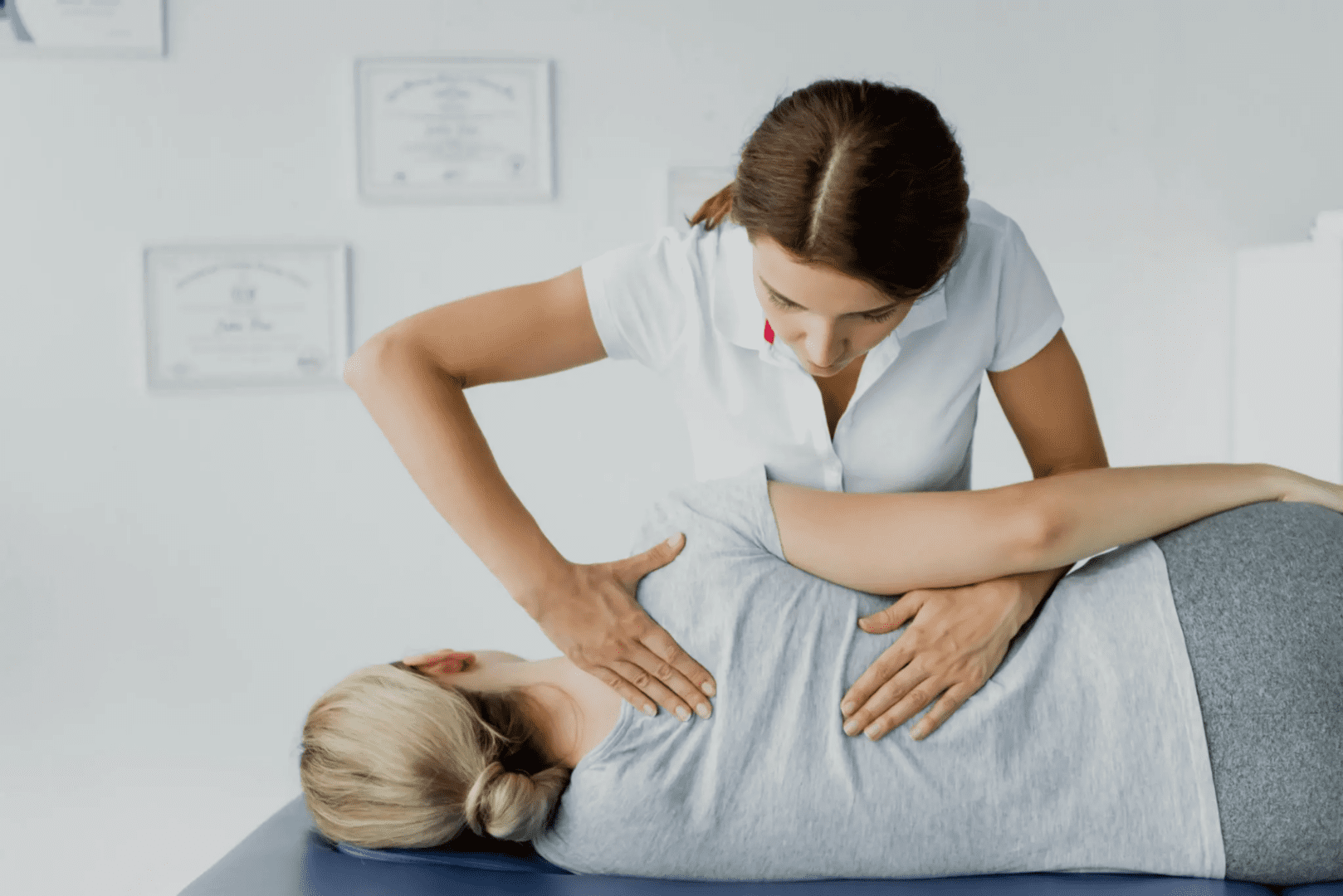 A woman is doing a back massage on the shoulder of another person.