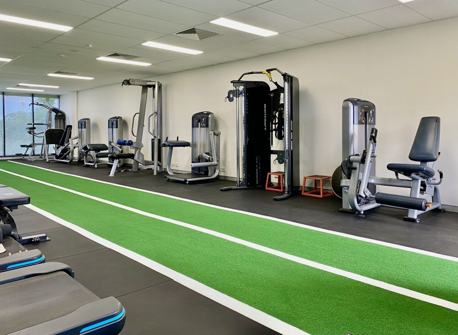 A gym with many machines and green carpet
