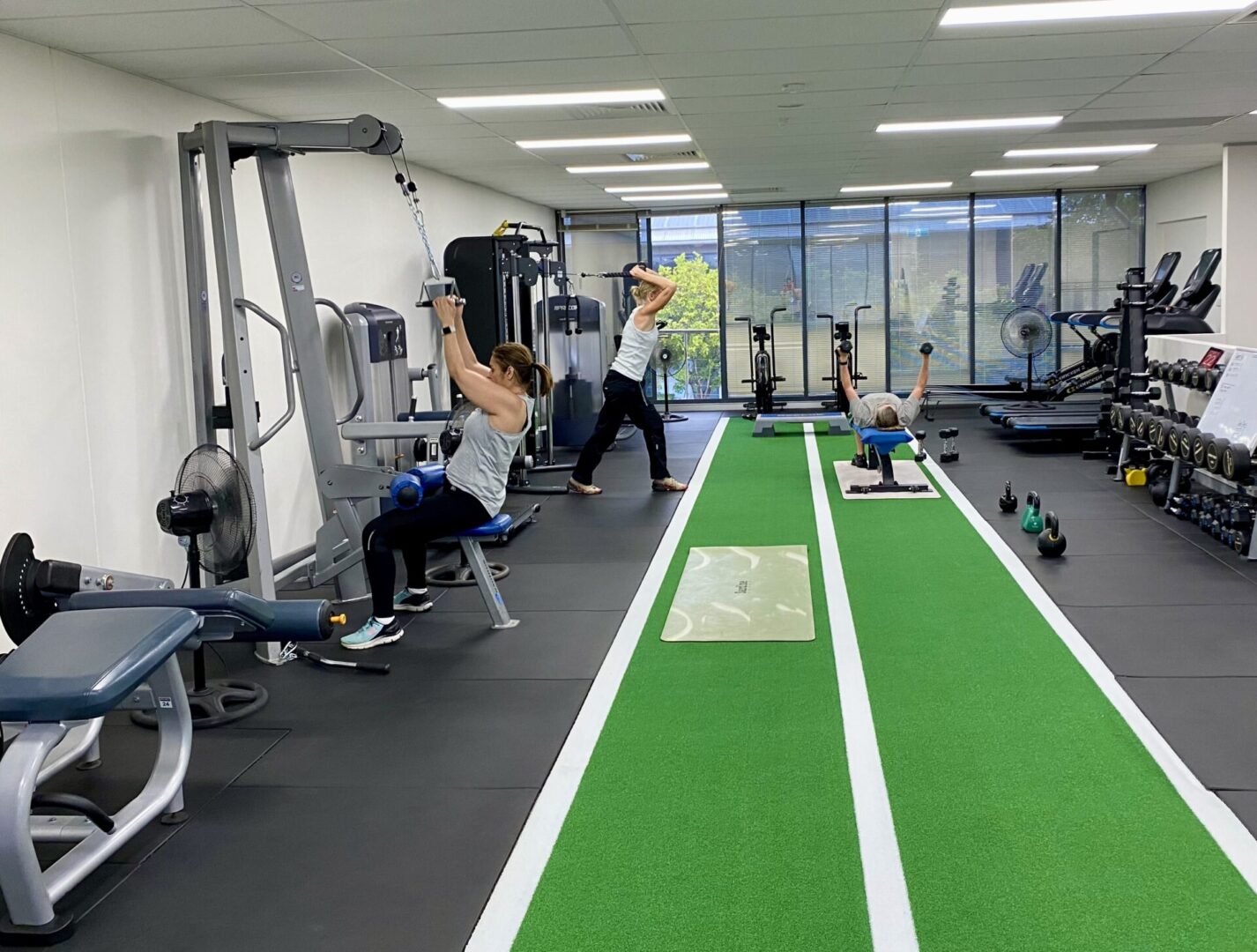 A group of people in the gym doing different exercises.