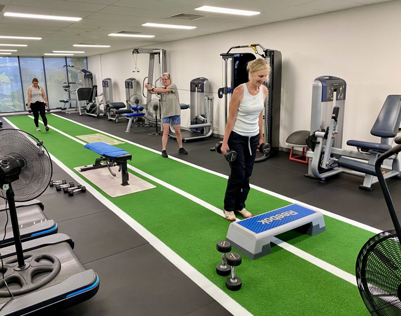 A woman standing on a step in the middle of an indoor gym.