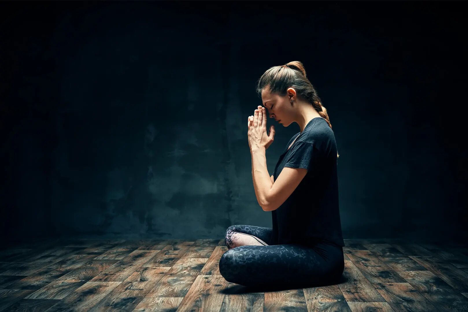 A woman sitting on the ground with her hands in front of her face.