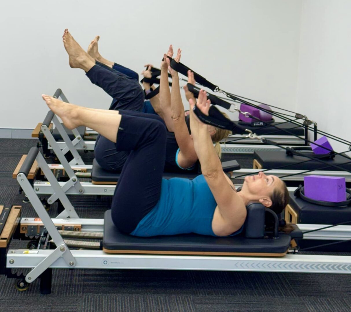 Two women are doing pilates on a reformer.